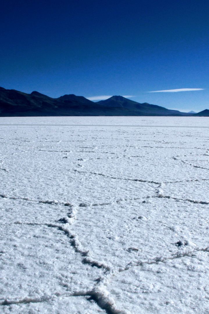 the vast expanse of flat land is covered in snow and mountains are seen in the distance