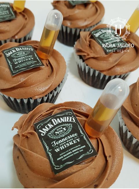 chocolate cupcakes with frosting and a bottle of jack daniels whiskey on top