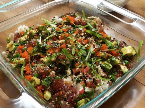 a glass casserole dish with vegetables and rice in it on a wooden table