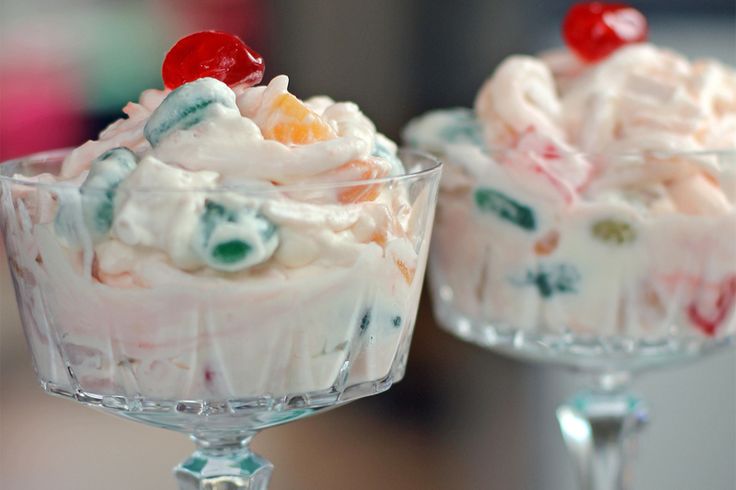 two desserts in small glass dishes on a checkered tablecloth with cherry decorations