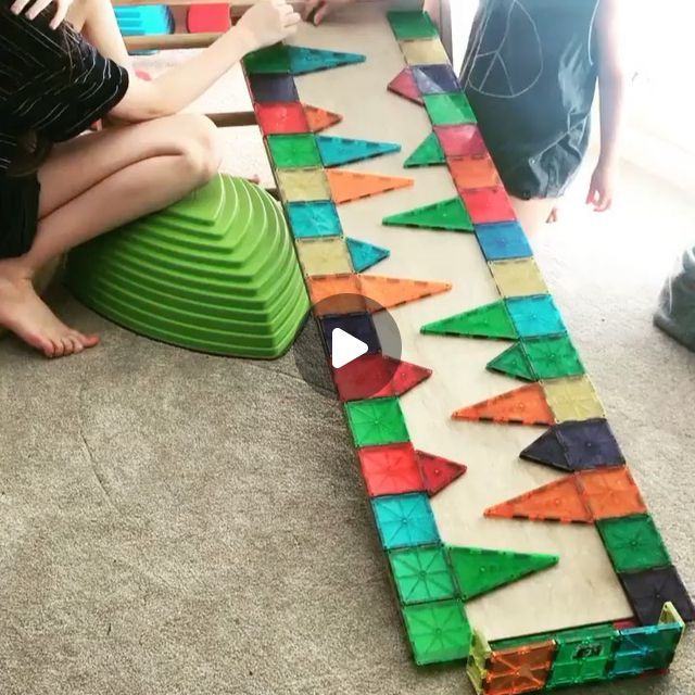 two children sitting on the floor playing with an art project made out of colored paper