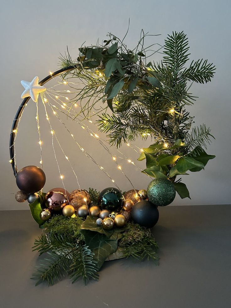 an arrangement of christmas ornaments and greenery on a table