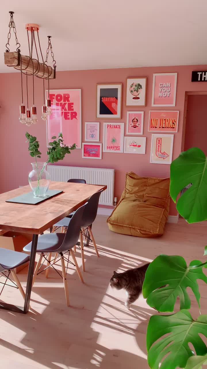 a dining room with pink walls and pictures on the wall