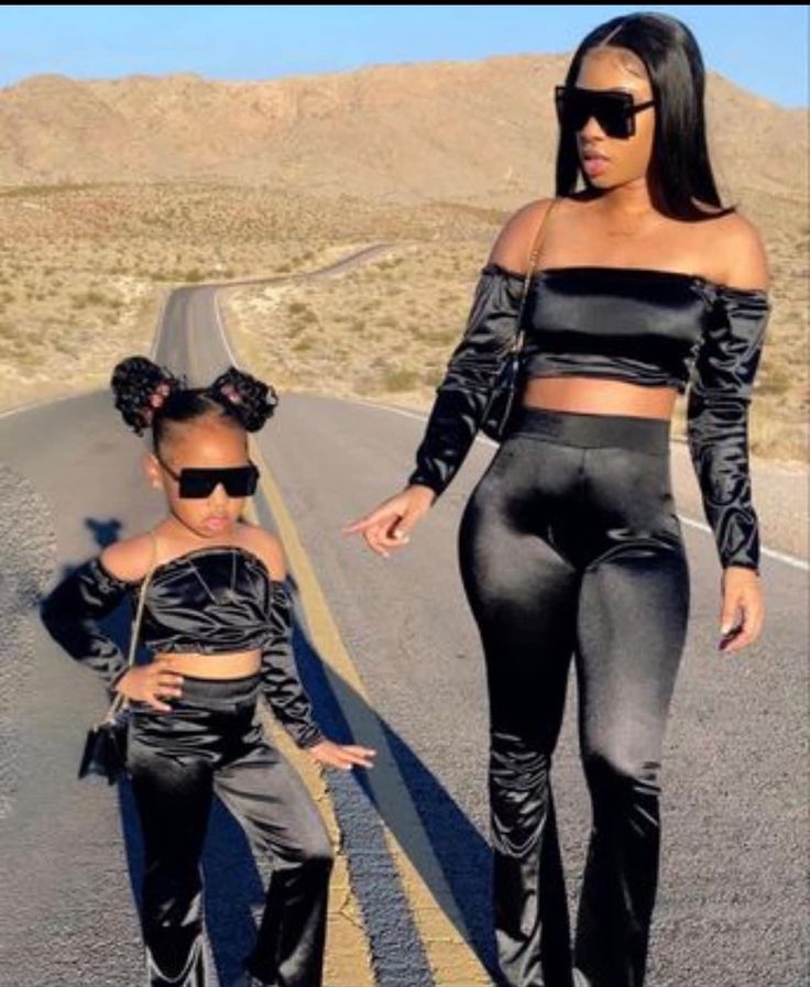 two women in black outfits are walking down the road