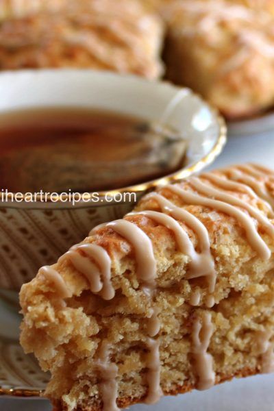 a close up of a piece of cake on a plate with a cup of tea in the background