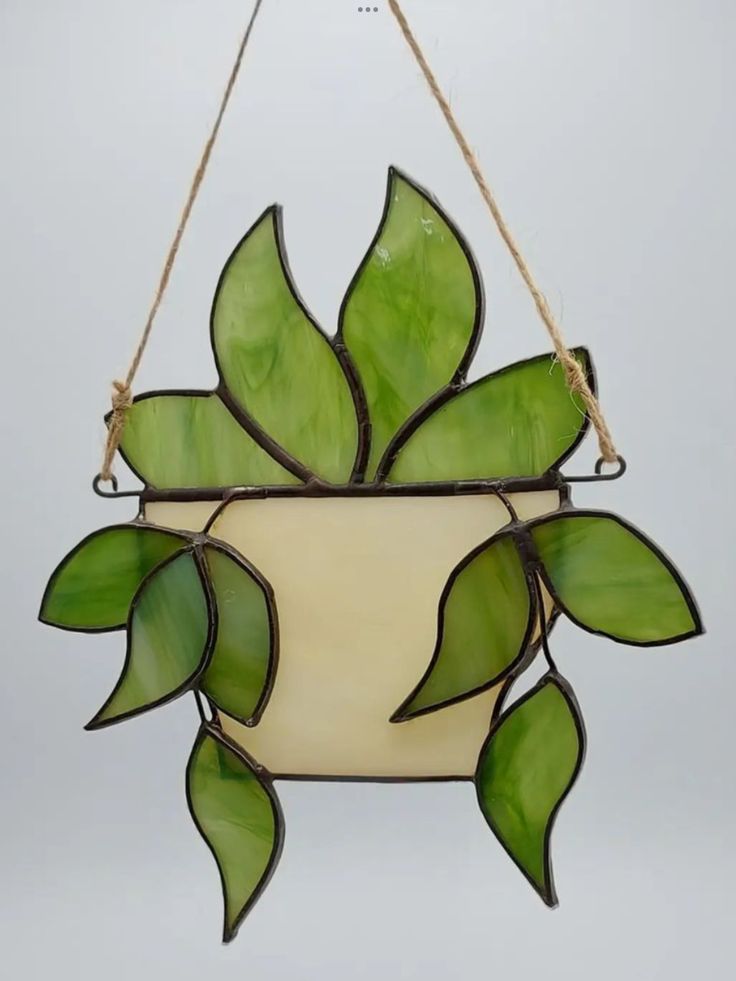 a hanging planter made out of stained glass with green leaves on the top and bottom