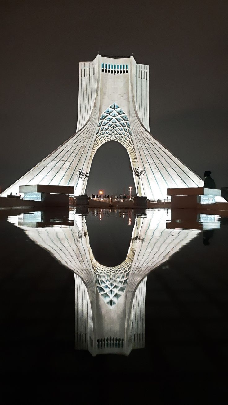 the building is reflecting in the water at night