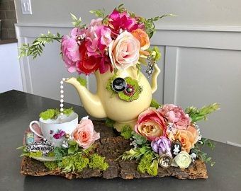 a teapot with flowers on top of a piece of wood