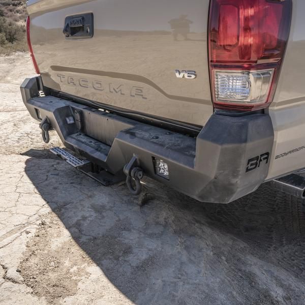 the back end of a silver truck parked on top of a dirt field