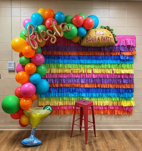 there is a party decoration with balloons and streamers in the shape of a rainbow