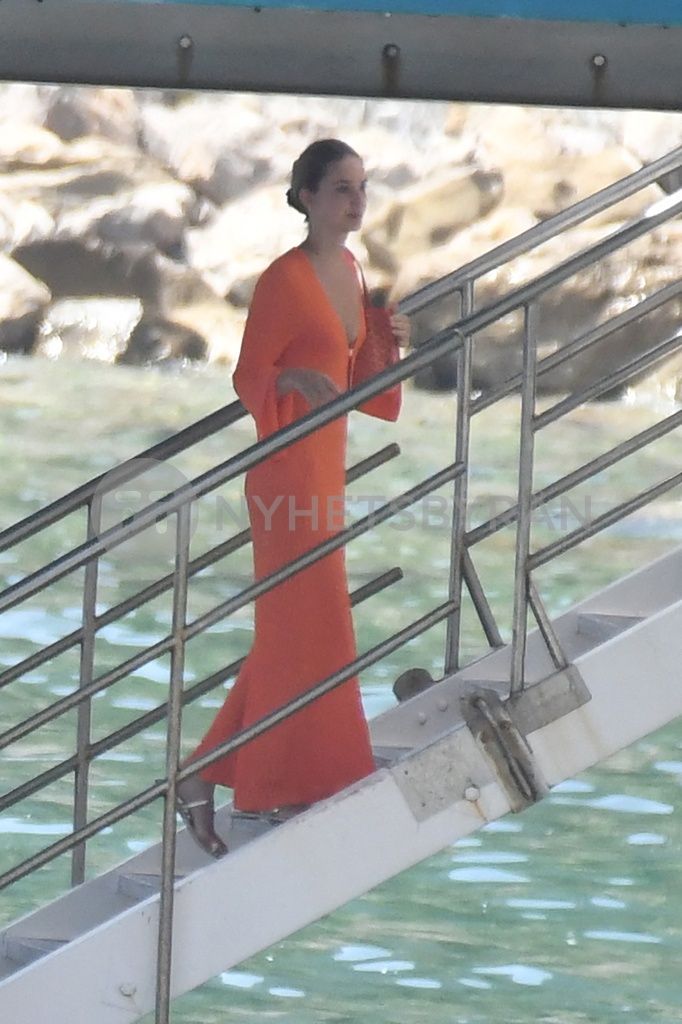 a woman in an orange dress is walking down the stairs