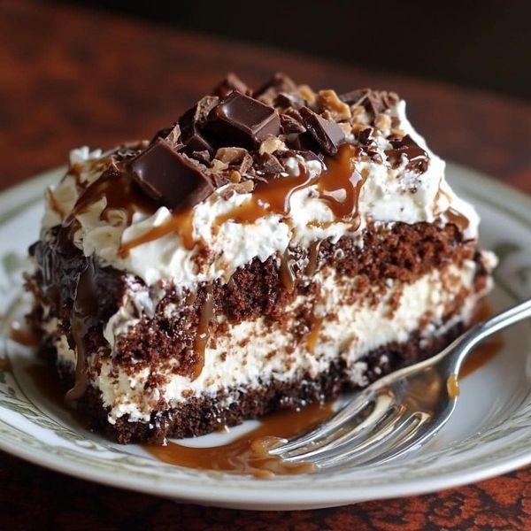 a piece of cake on a white plate with chocolate and caramel drizzle