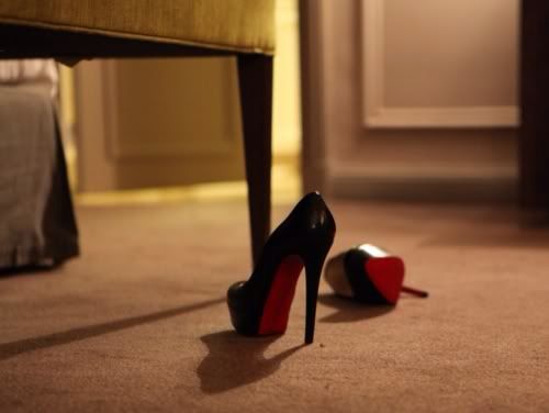 pair of black and red high heeled shoes sitting on the floor in front of a chair