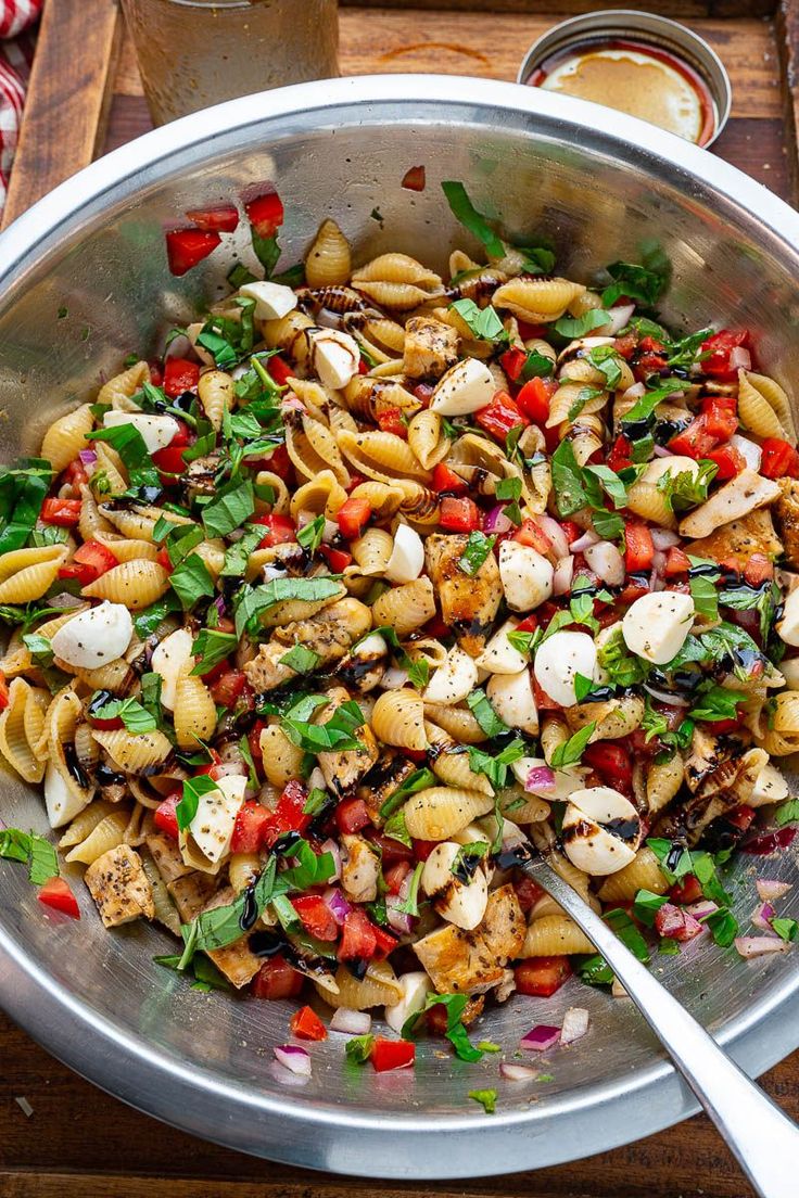 a large bowl filled with pasta salad on top of a wooden table