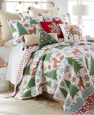 a bed covered in christmas themed pillows and blankets with deers, snowflakes and trees on them