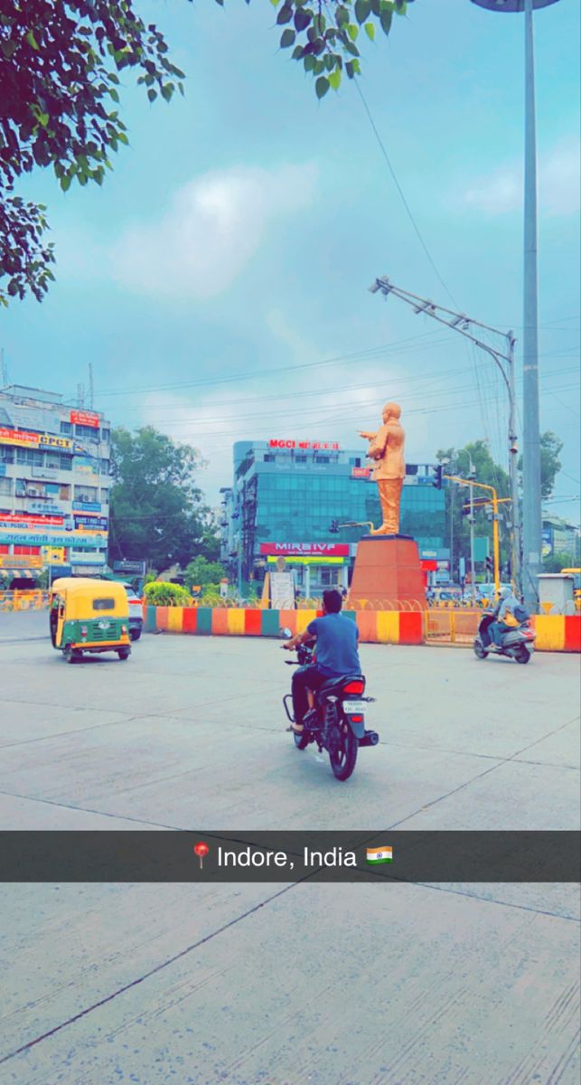 a man riding a motorcycle down the middle of a street next to tall buildings and traffic lights