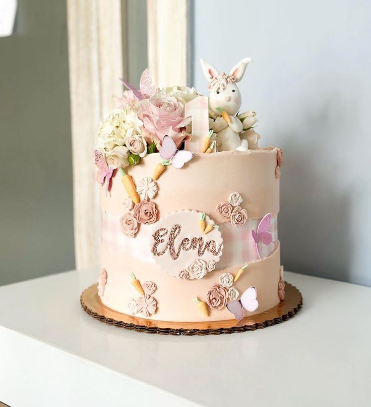 a pink cake decorated with flowers and an animal topper