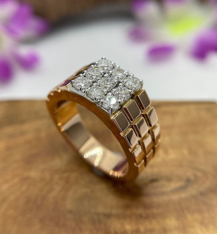 a diamond ring sitting on top of a wooden table next to purple and white flowers