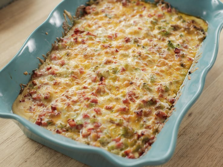 a casserole dish with cheese and vegetables in it on a wooden table top