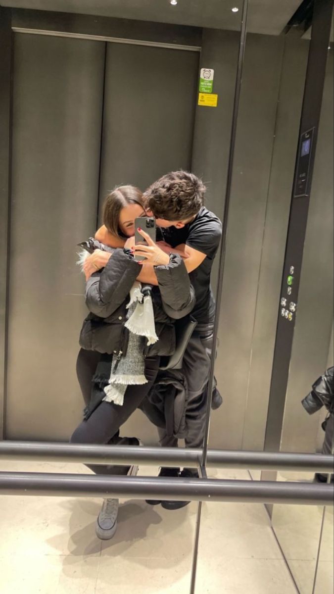 two people are hugging in front of a mirror