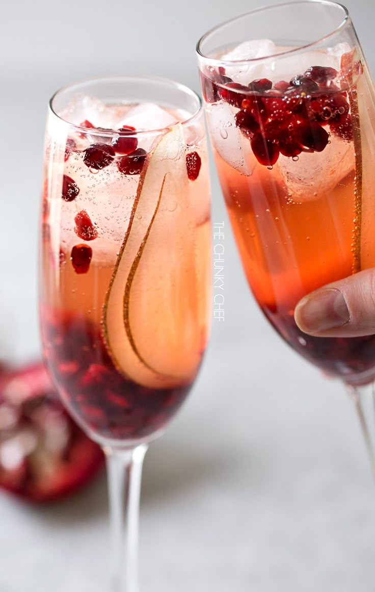 two wine glasses filled with pomegranate and ice