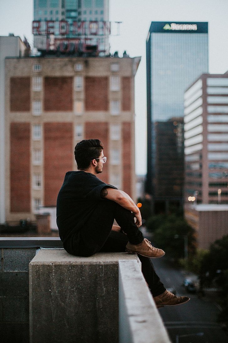 a man sitting on top of a cement block next to tall buildings in the city