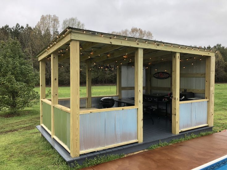 a small wooden structure sitting on top of a grass covered field next to a swimming pool