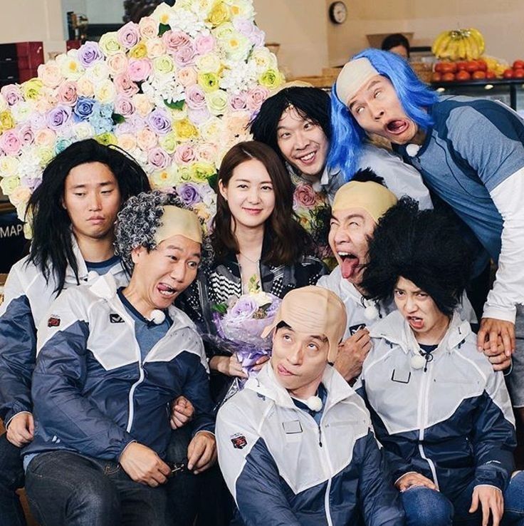 a group of people posing for a photo with flowers on the wall in the background