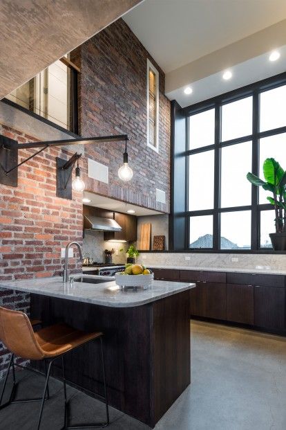 an open kitchen and dining area with brick walls, floor to ceiling windows, and modern appliances