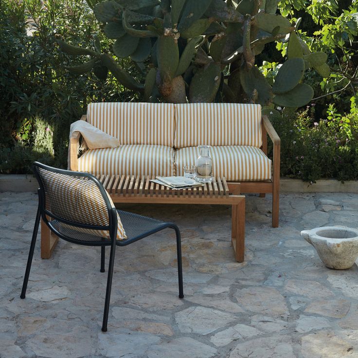 a couch sitting on top of a stone patio next to a potted plant