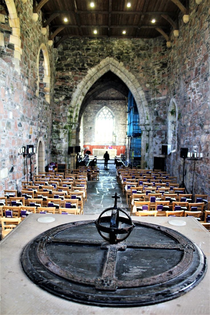 the inside of an old church with rows of chairs and a wheel on the floor