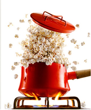 a red bucket filled with popcorn sitting on top of a table