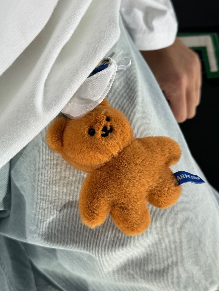 a teddy bear is attached to the back of a person's shirt with an id tag on it