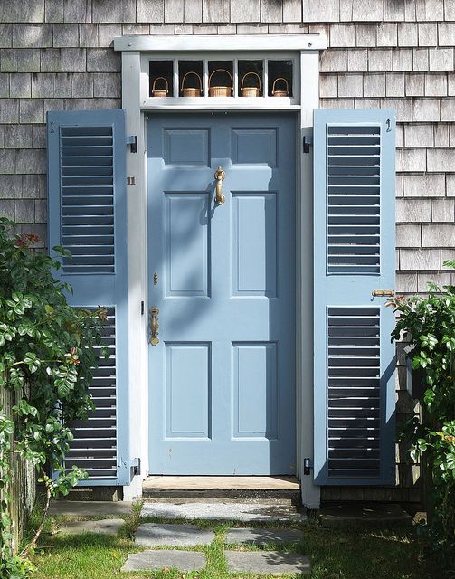 a blue door with shutters and pots on it