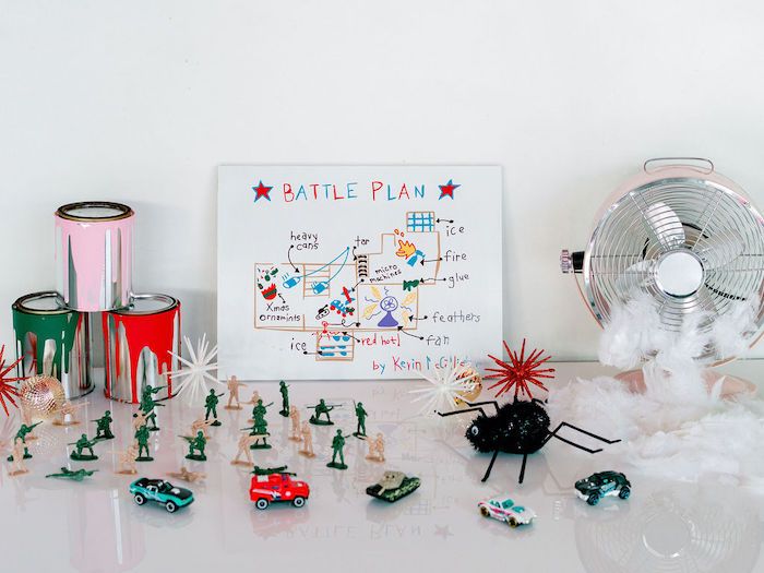 a white table topped with toy figurines next to a fan and other items