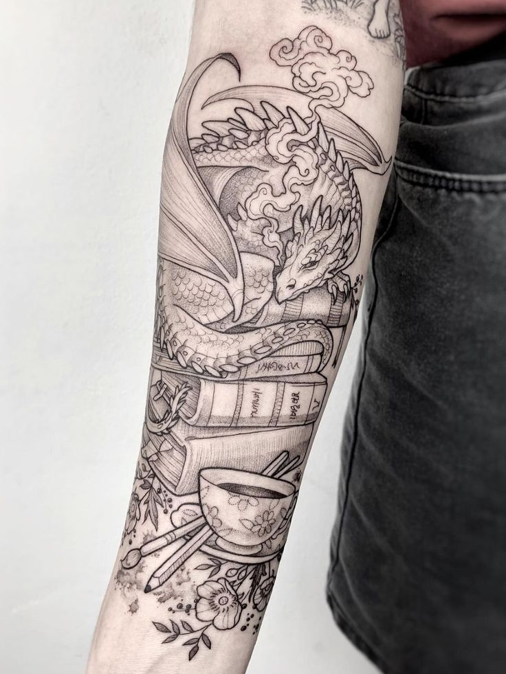 a person with a tattoo on their arm holding a book and coffee cup in front of them