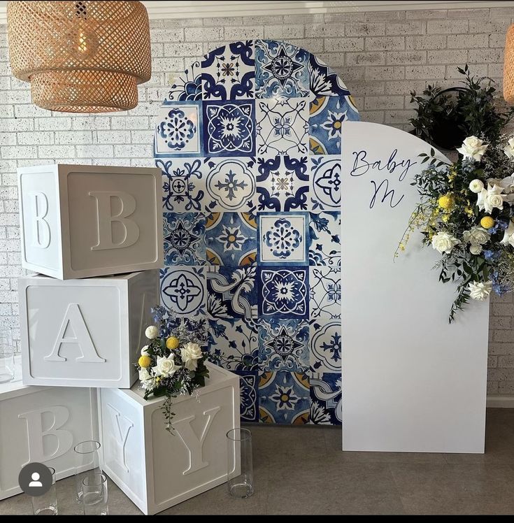 the baby shower is decorated with blue and white tiles, flowers and letters on it