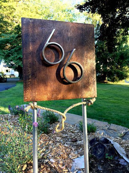 a wooden sign with the number six on it in front of some grass and trees