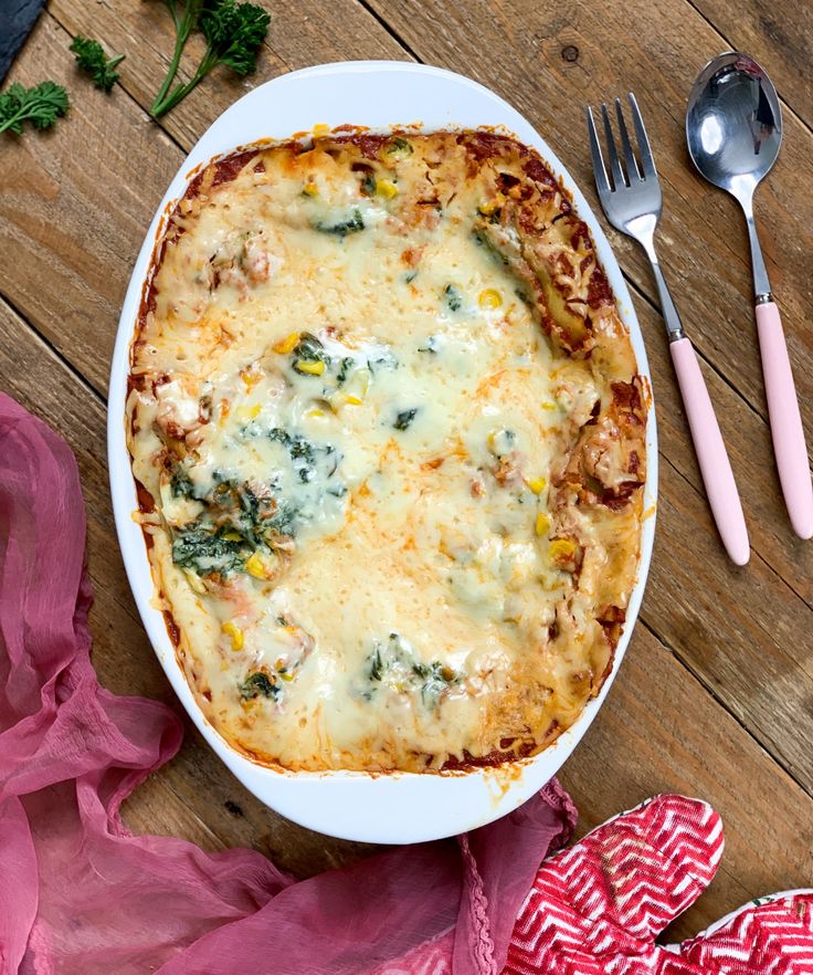 a casserole dish with broccoli, cheese and other toppings on a wooden table