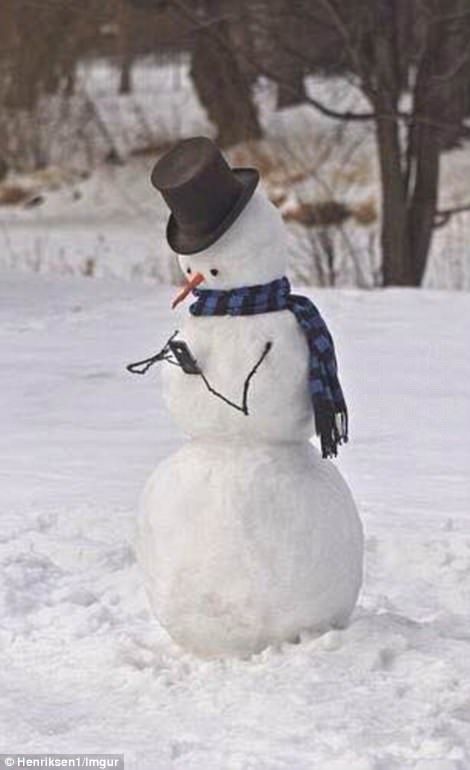 a snowman with a hat and scarf on standing in the snow wearing a top hat