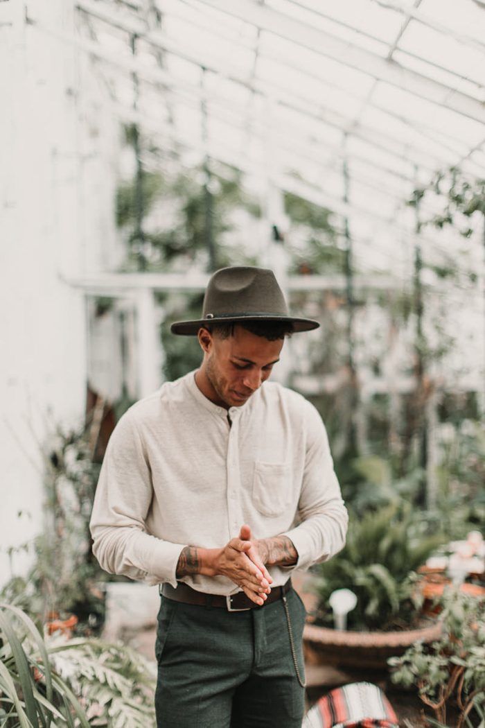 a man standing in a greenhouse looking down at his watch