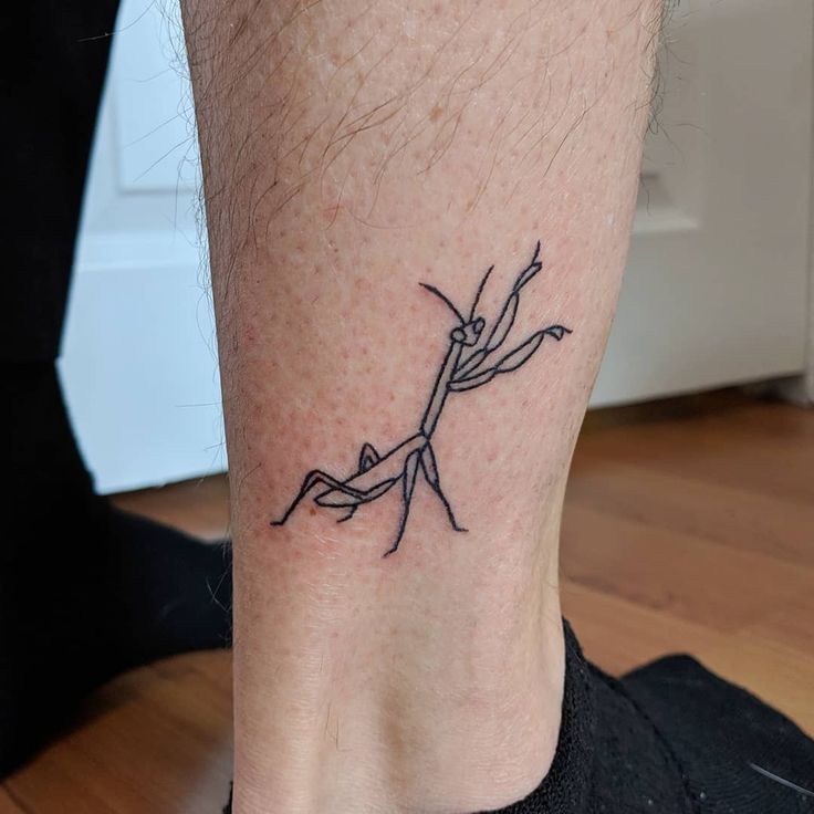 a person with a small tattoo on their ankle that has an image of a praying mantissa