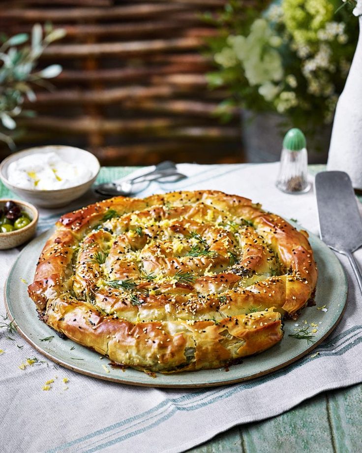 a pizza sitting on top of a plate next to a knife and bowl filled with food