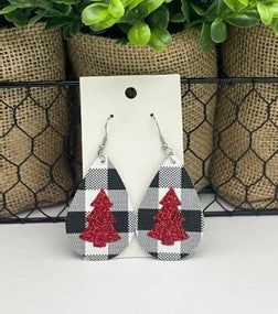 pair of earrings with red and black checkerboard design on the front, sitting next to a potted plant