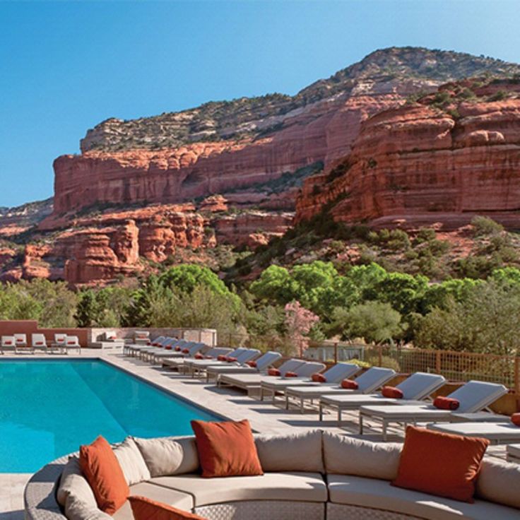 an outdoor pool with chaise lounges and mountains in the background