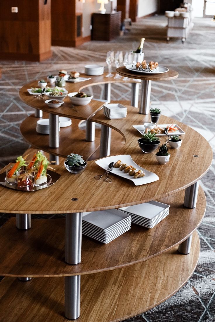 a wooden table topped with lots of plates filled with different types of food on top of it