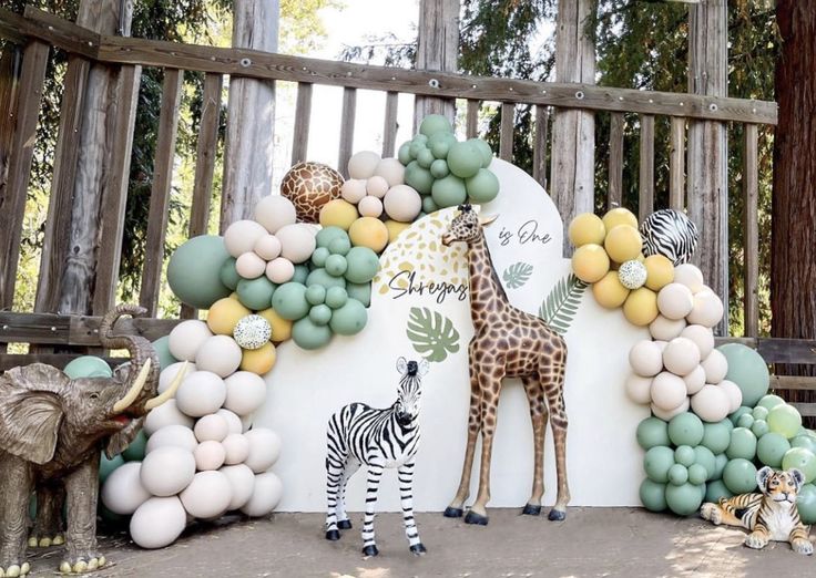 a giraffe and zebra are standing in front of an arch made out of balloons