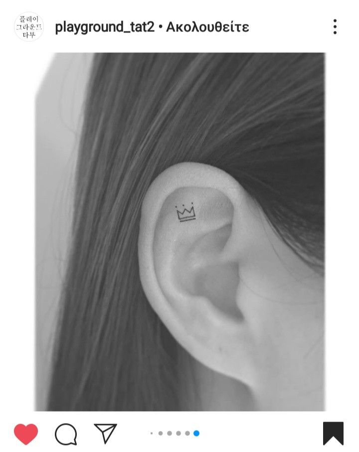 a woman's ear with a small crown tattoo on it