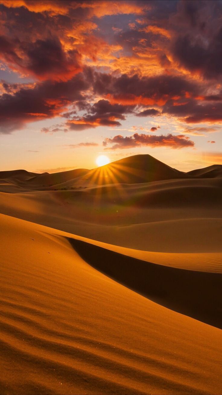 the sun is setting over sand dunes in the desert