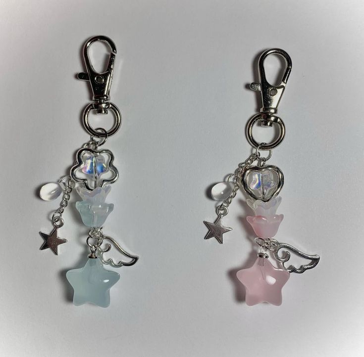 two key chains with charms attached to them on a white surface, one is pink and the other is blue